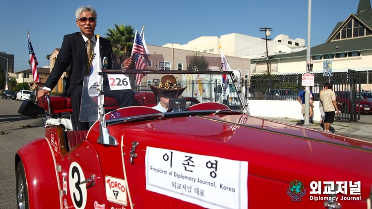 &nbsp;Chairman Lee Jon-yong of the Diplomacy Journal stands on a leading car of the parade responding to the warm welcome of the visitors