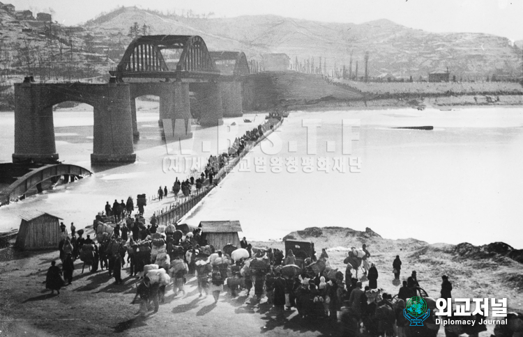 An endless column of refugees cross the provisional brodge over the Han River built beside the damaged span of the<br>
bridge. Korea, December 1950<br>
&nbsp;