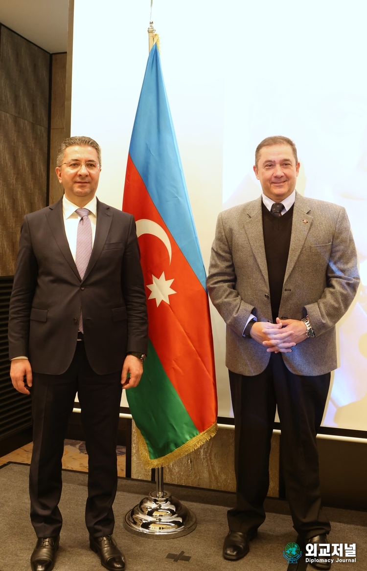 Amb. Ramin M. Hasanov of Azerbaijan (left) and Amb. Murat Tamer of Turkiye take a commemorative photo with the Azerbaijani flag in the center.